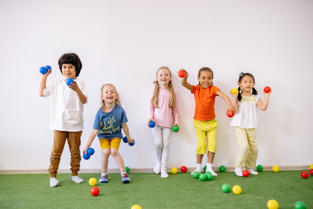 Happy diverse children playing with colorful balls indoors, showcasing fun and friendship.